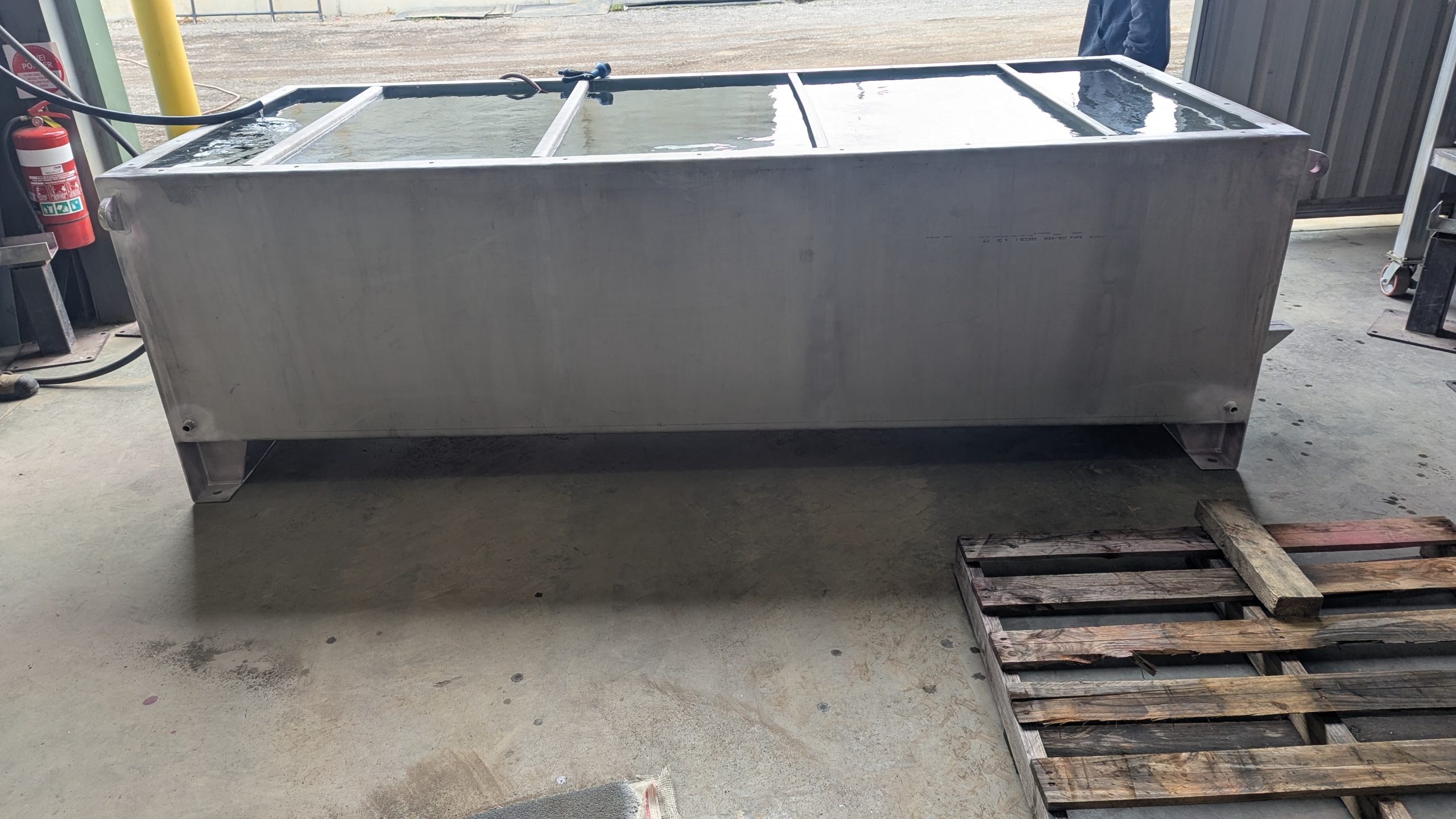 Stainless steel tank filled with water during hydrostatic testing in a fabrication facility.